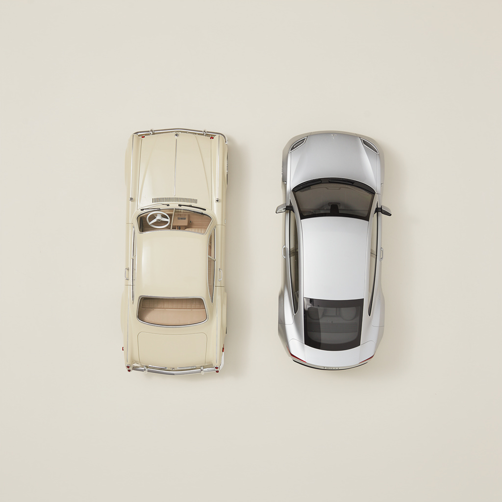 A vintage cream-colored car and a modern sleek silver car are placed side by side, viewed from directly above.