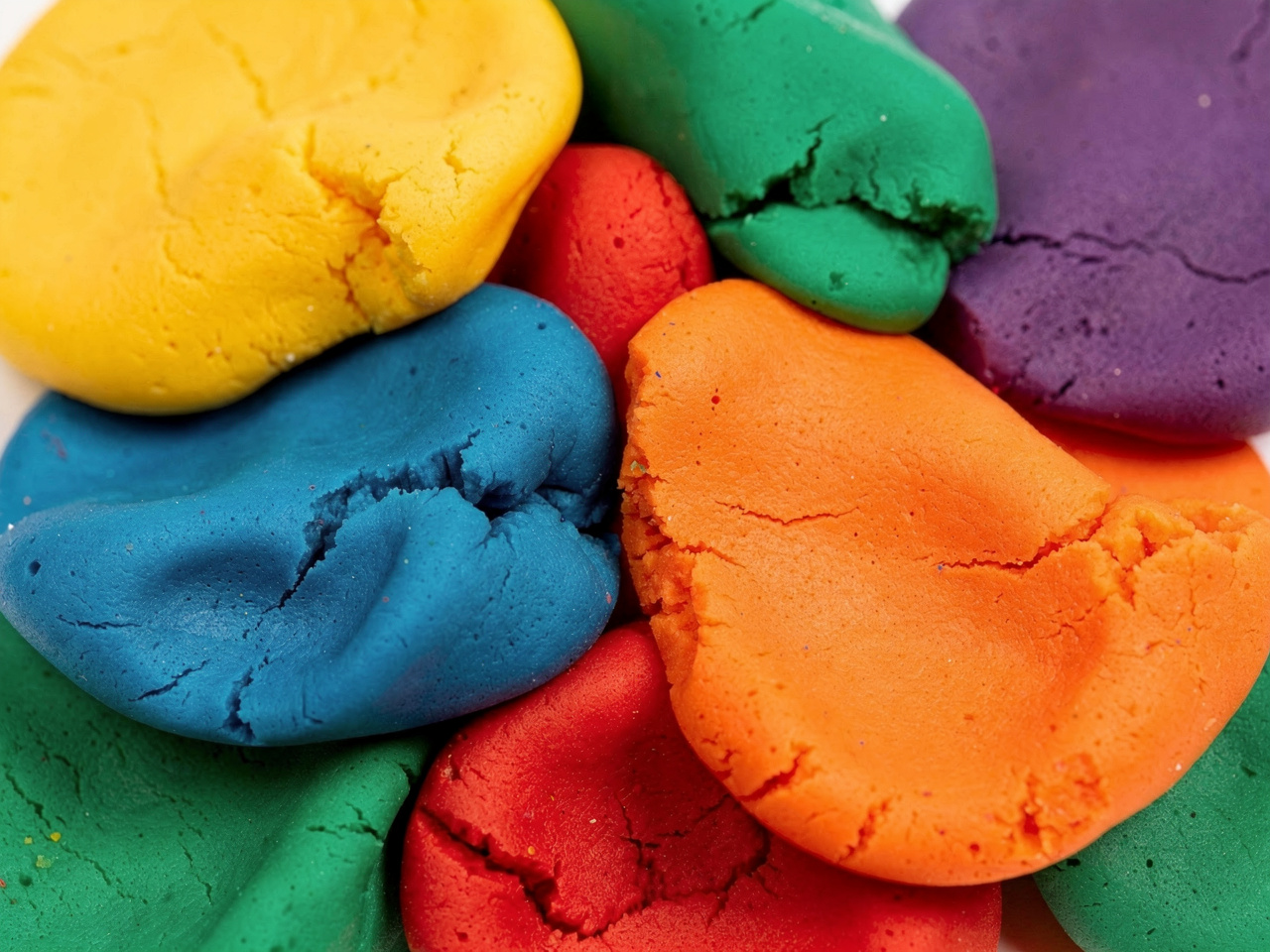Colorful blobs of flattened modeling clay in shades of yellow, blue, orange, red, green, and purple.