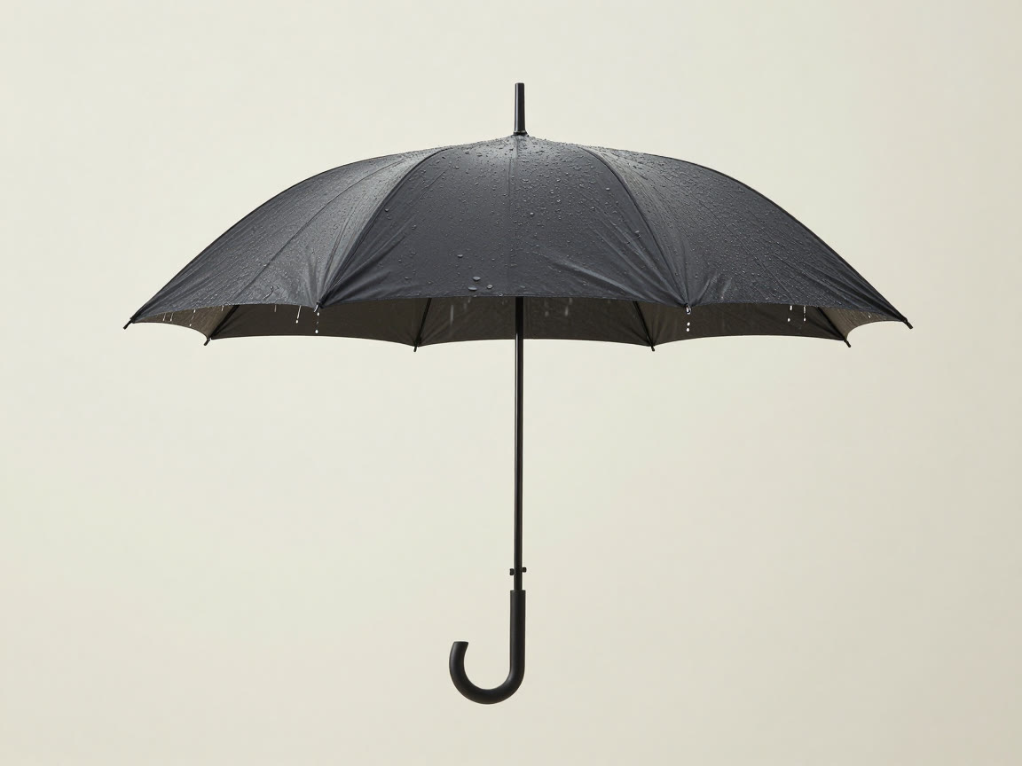 An open black umbrella with water droplets scattered across its canopy and dripping from the edges.